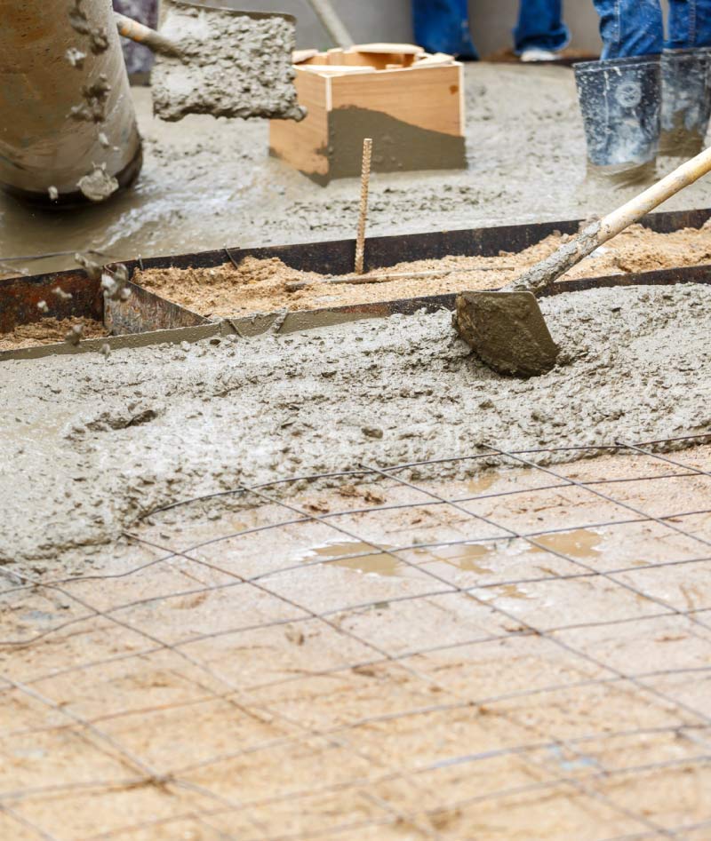 Newly poured concrete patio slab in a residential backyard with wood fence