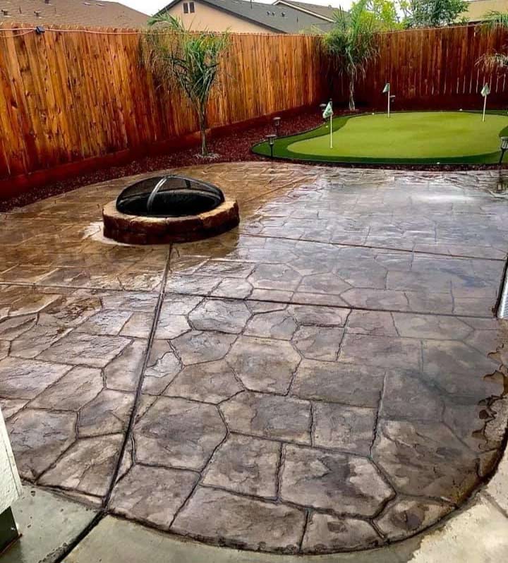 Stamped concrete backyard patio with stone-pattern finish, fire pit, and putting green