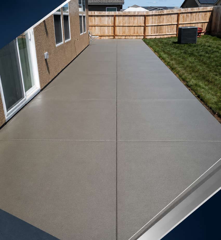 Newly poured concrete patio slab in a residential backyard with wood fence